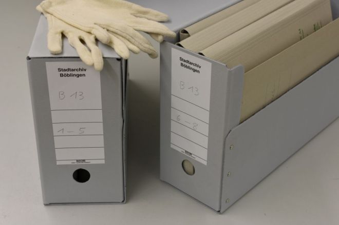 Zwei Archivboxen mit Handschuhen und Akten