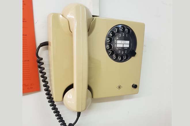Altes Telefon in beige and er Wand hängend
